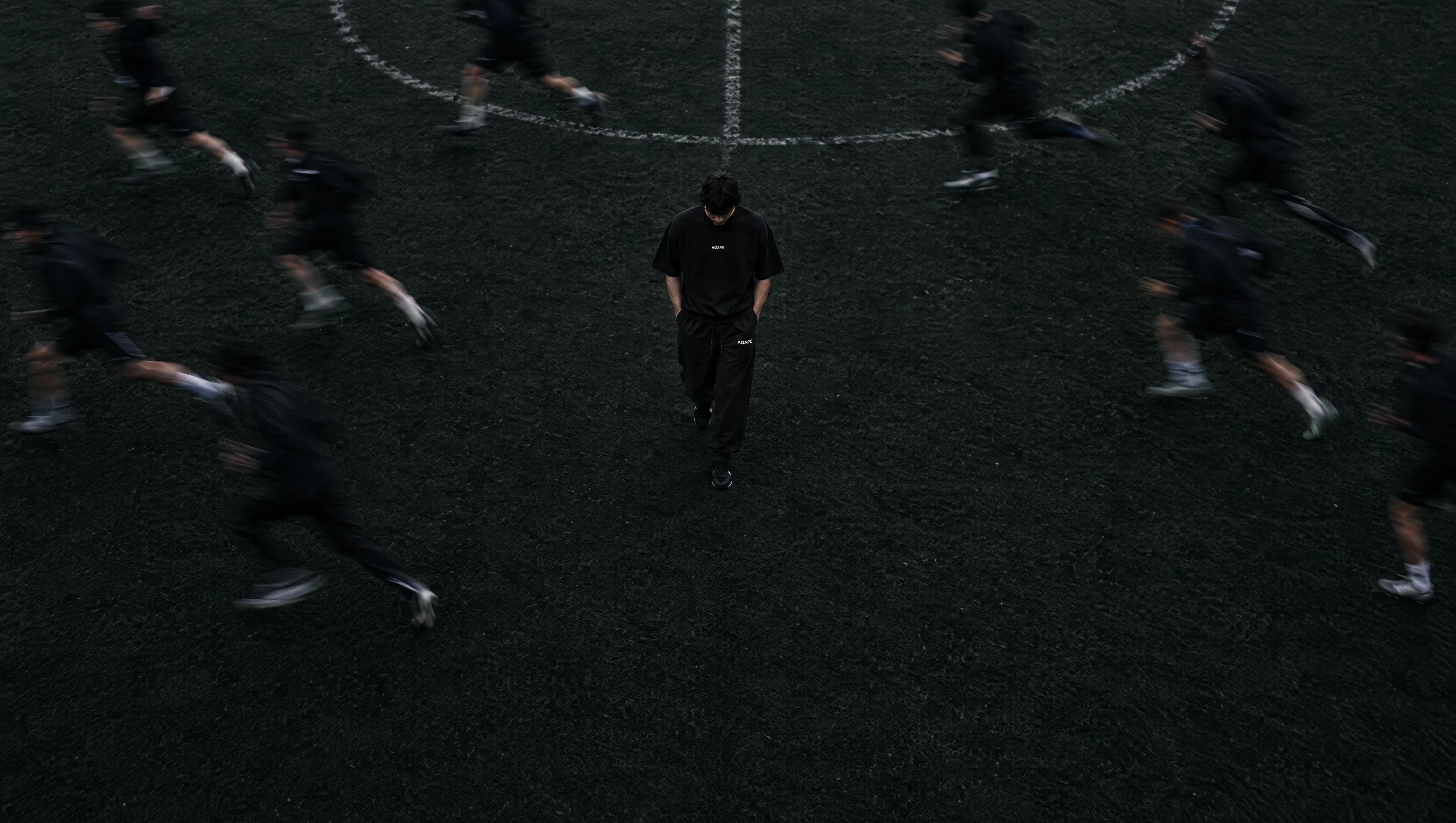 AGAPE athlete walking across a football pitch as teammates sprint past