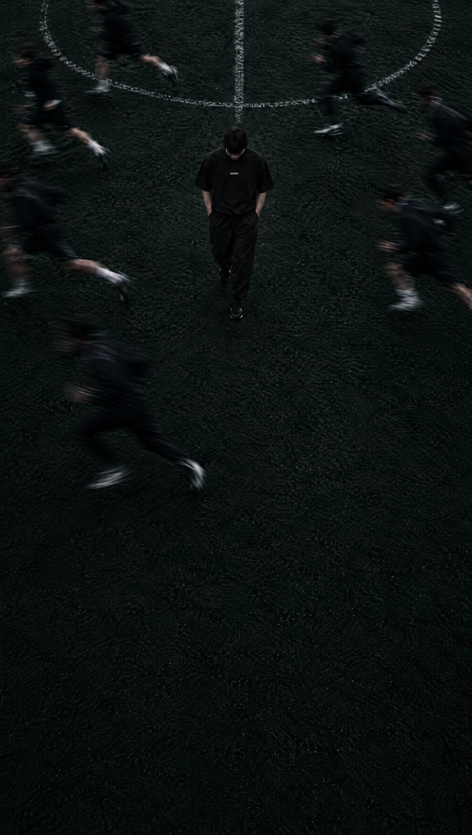AGAPE athlete walking across a football pitch as teammates sprint past